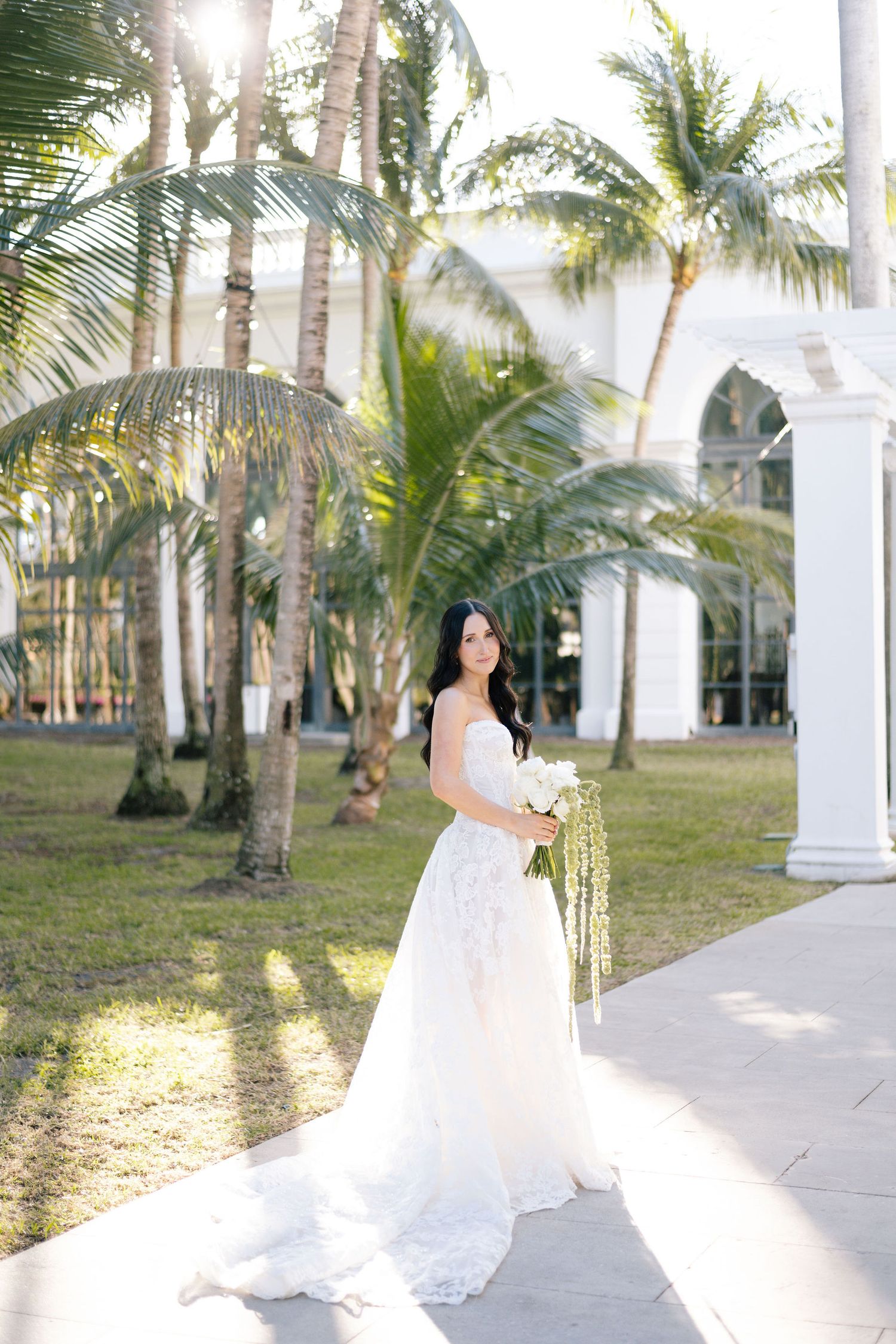Flowing white wedding dress photographed in sequence against tropical palm garden backdrop.