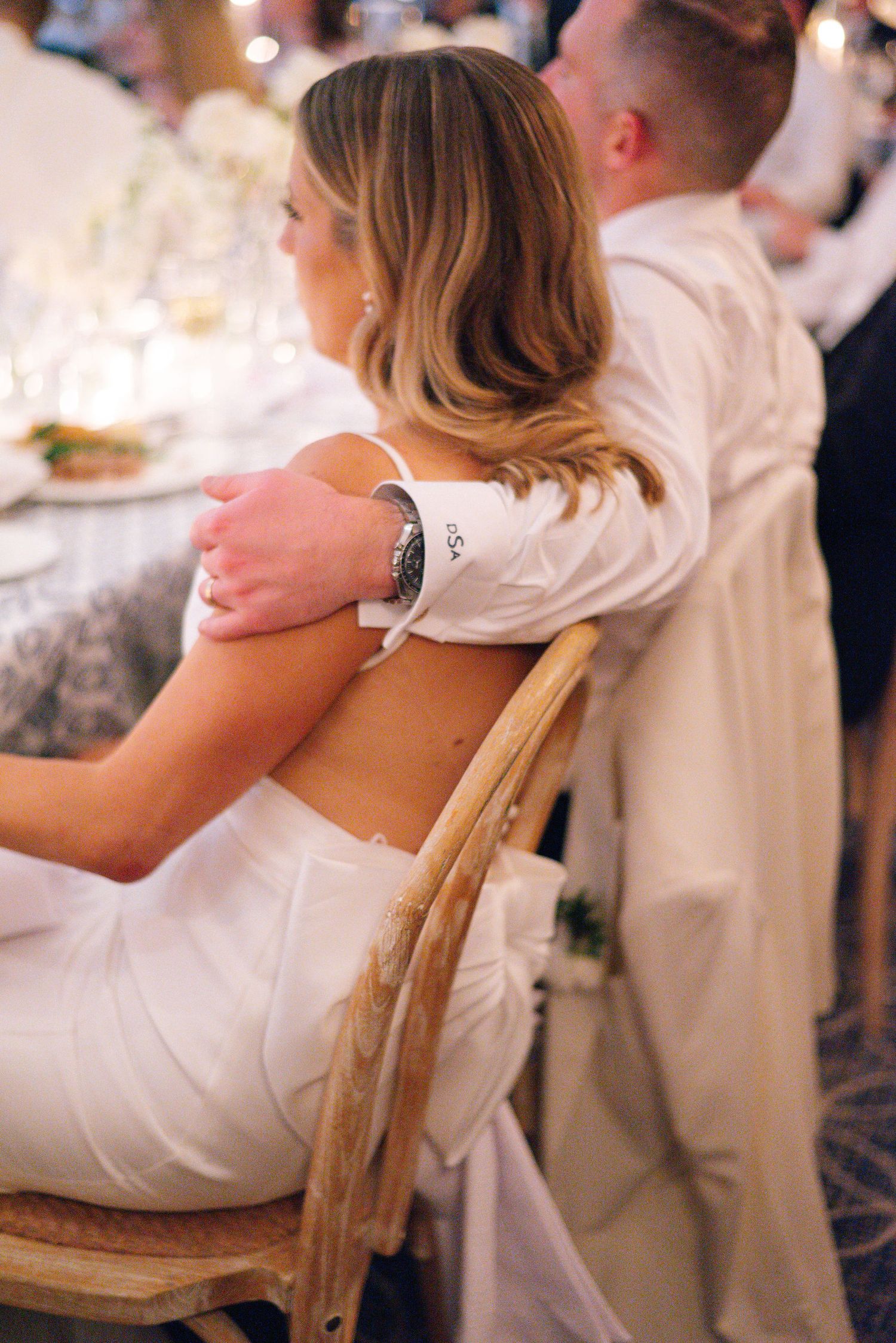 Elegant wedding reception details showing guests seated at tables with white decor and ambient lighting.