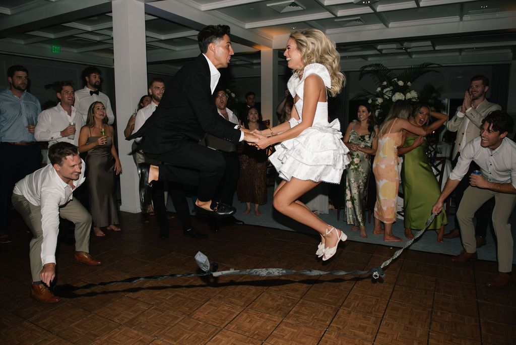 Wedding guests dance and celebrate on a dimly lit dance floor during a reception party.