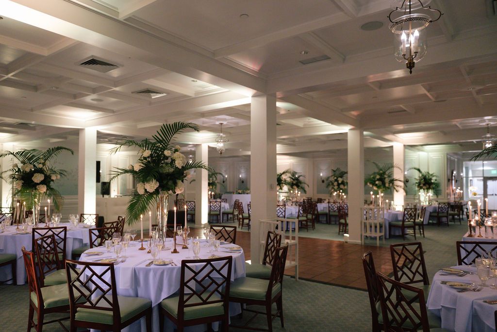 Spacious banquet hall set up for a formal event with round tables and elegant white linens.
