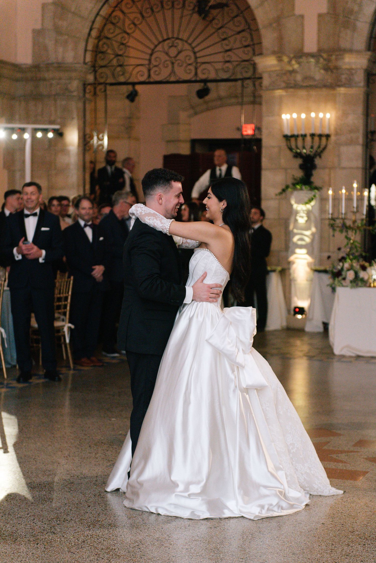 Wedding reception dance floor in an elegant ballroom with stone archways and decorative ironwork.