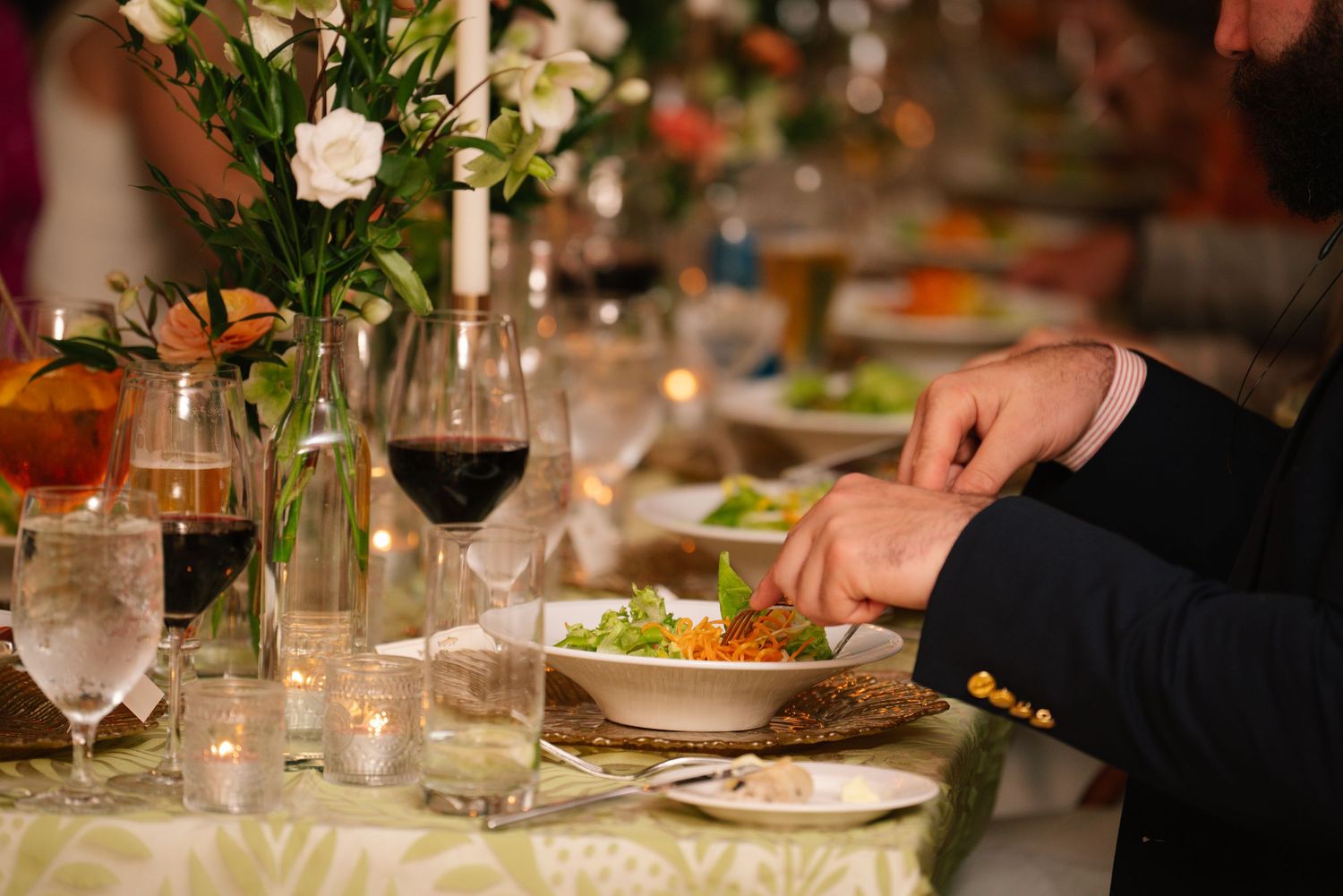 Elegant table settings at a formal dinner party with wine glasses, plates and floral arrangements.