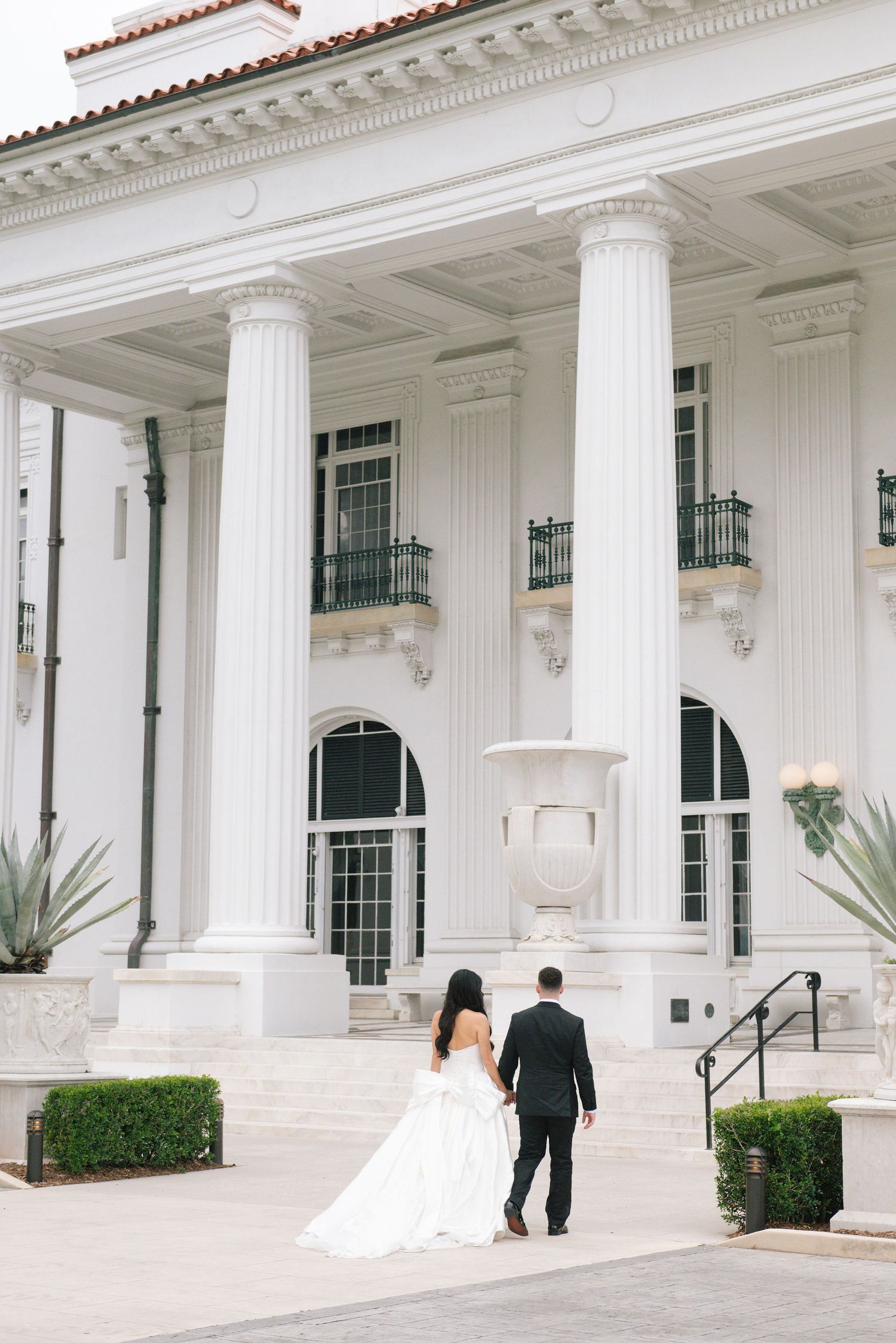White colonial mansion with grand columns and arched windows on a sunny day.