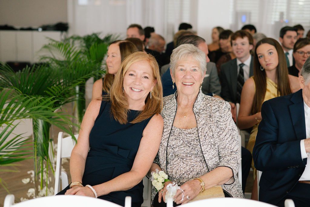 Wedding guests seated in formal attire at an elegant indoor ceremony.