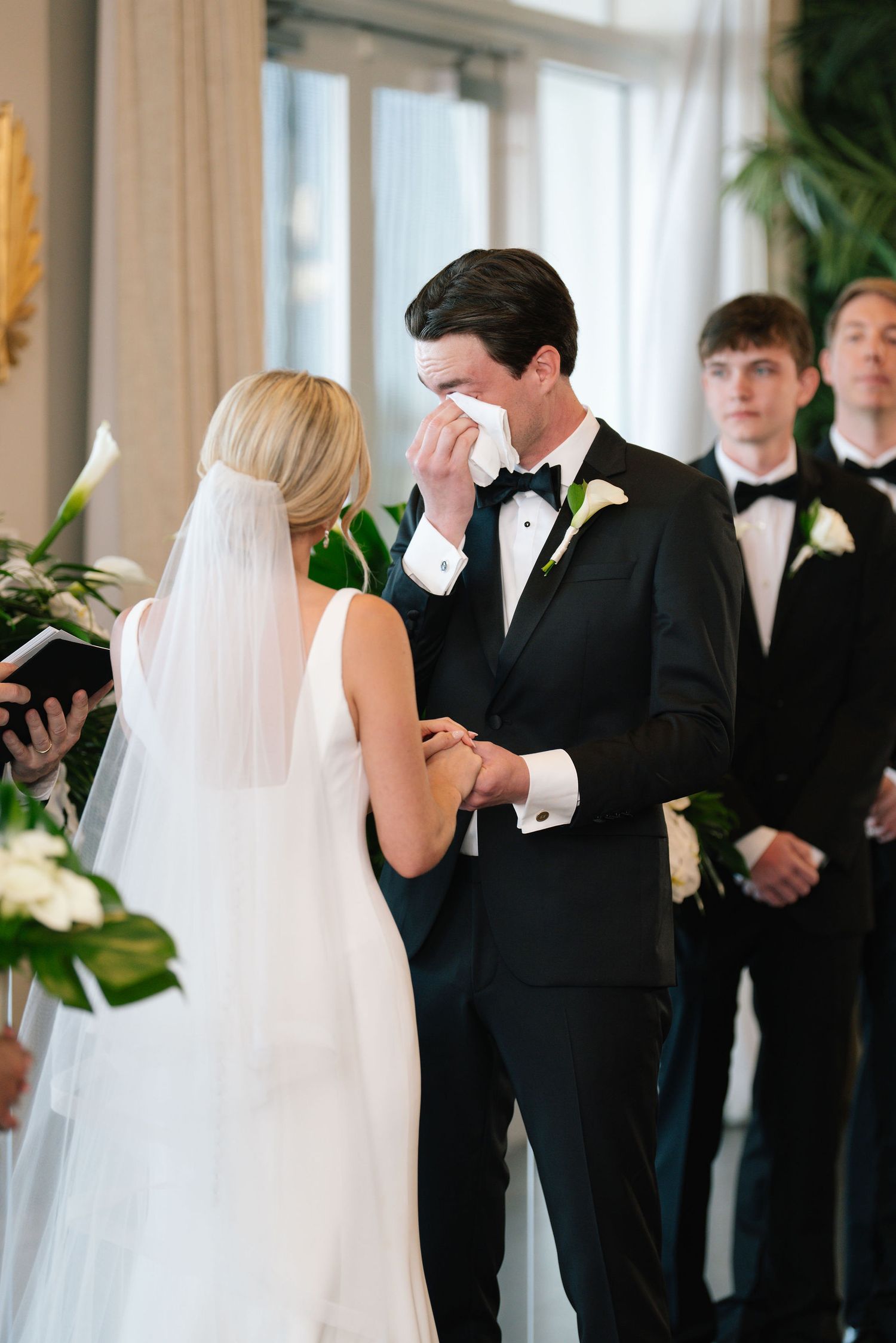 Emotional wedding ceremony moment between couple in formal attire during indoor service.