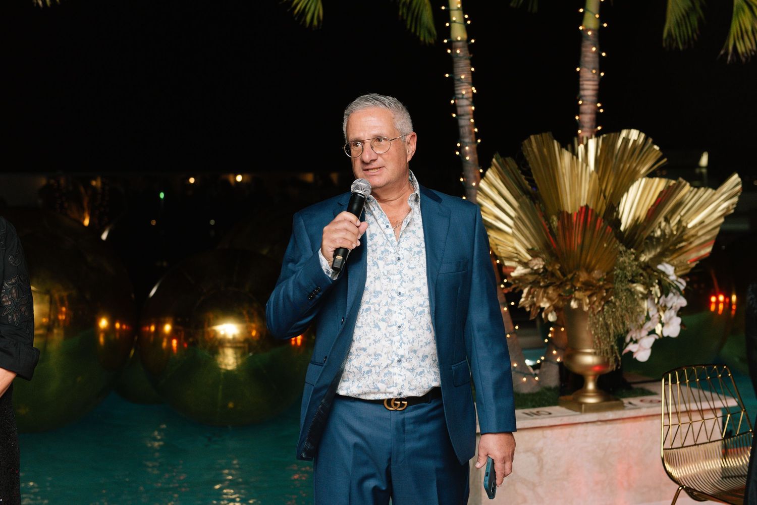 Evening outdoor reception setup with glowing lights and tropical palm trees creating an elegant ambiance.