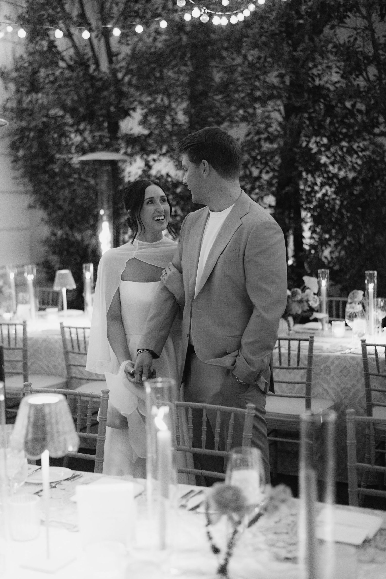 Outdoor wedding reception setting with elegant table arrangements and natural greenery.
