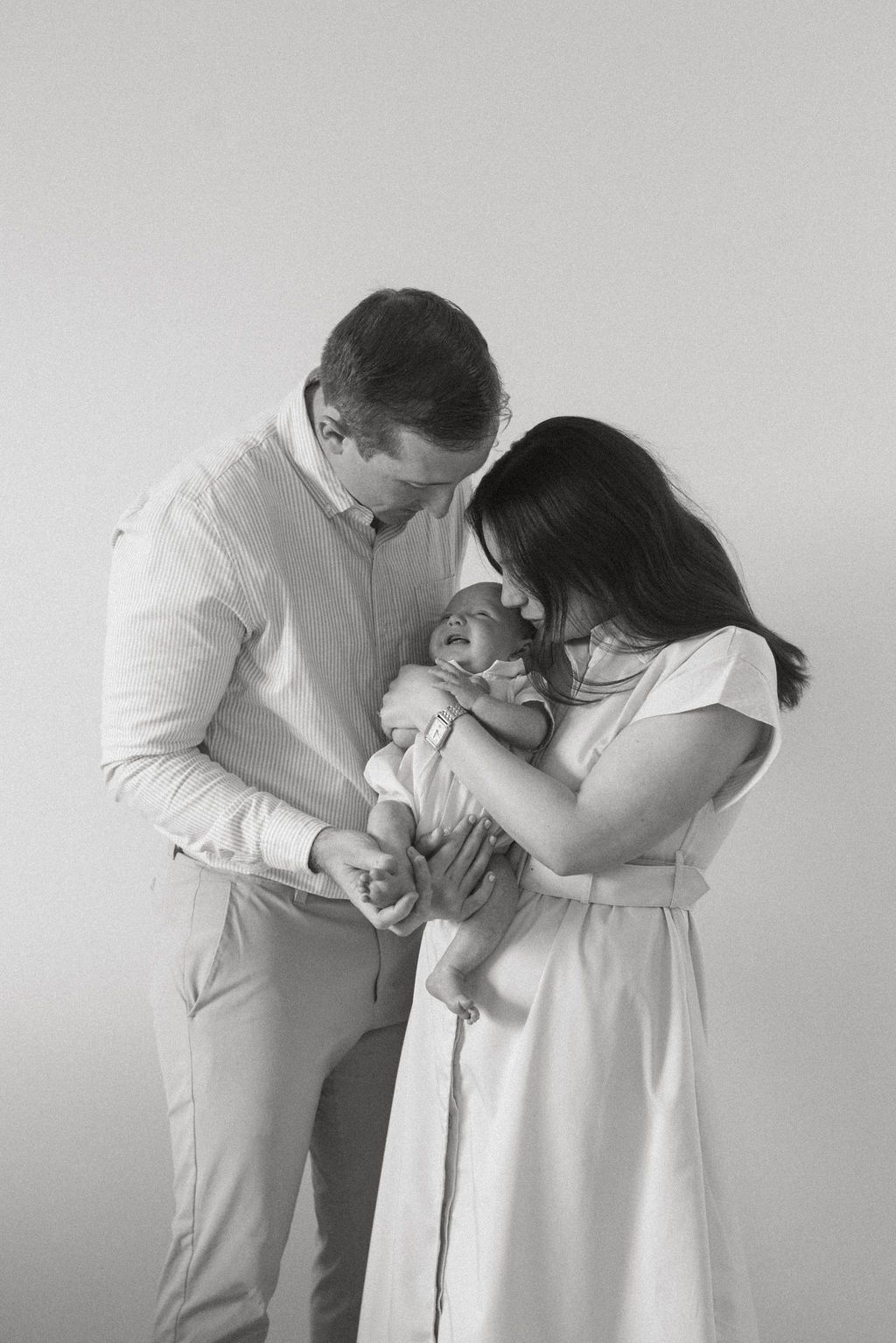 Black and white series of parents sharing intimate moments with their newborn baby.