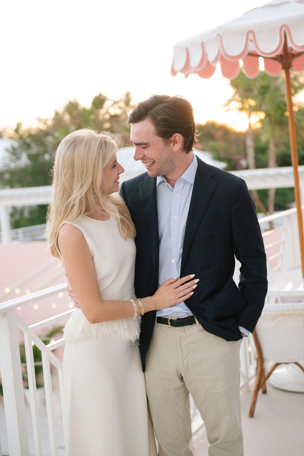 Romantic moment captured on balcony with decorative coral umbrella at sunset.