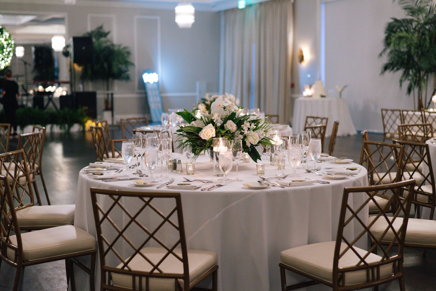 Modern wedding reception hall with round tables and geometric patterned chairs.