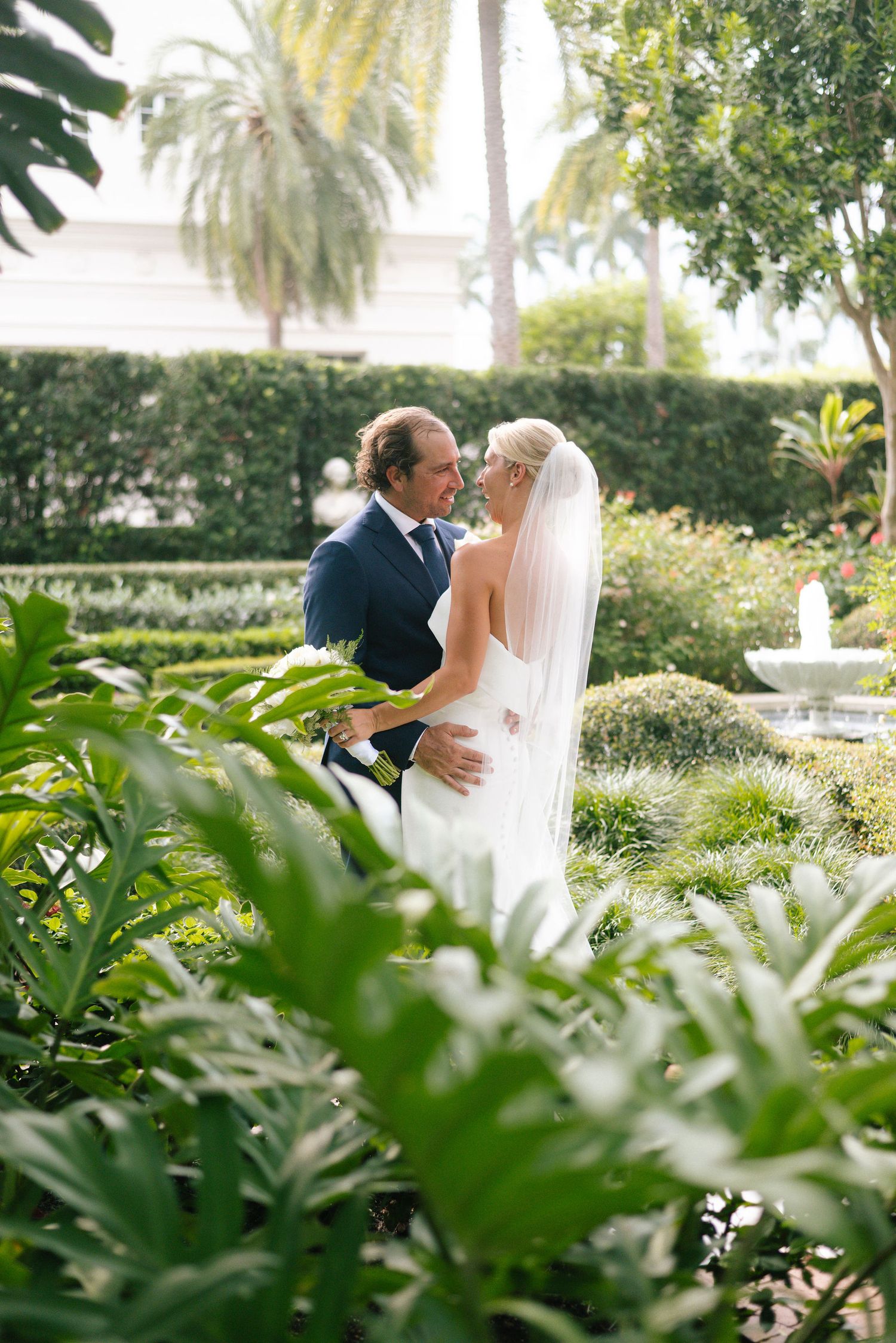 Intimate wedding moment captured in a tropical garden with palm trees and lush foliage.