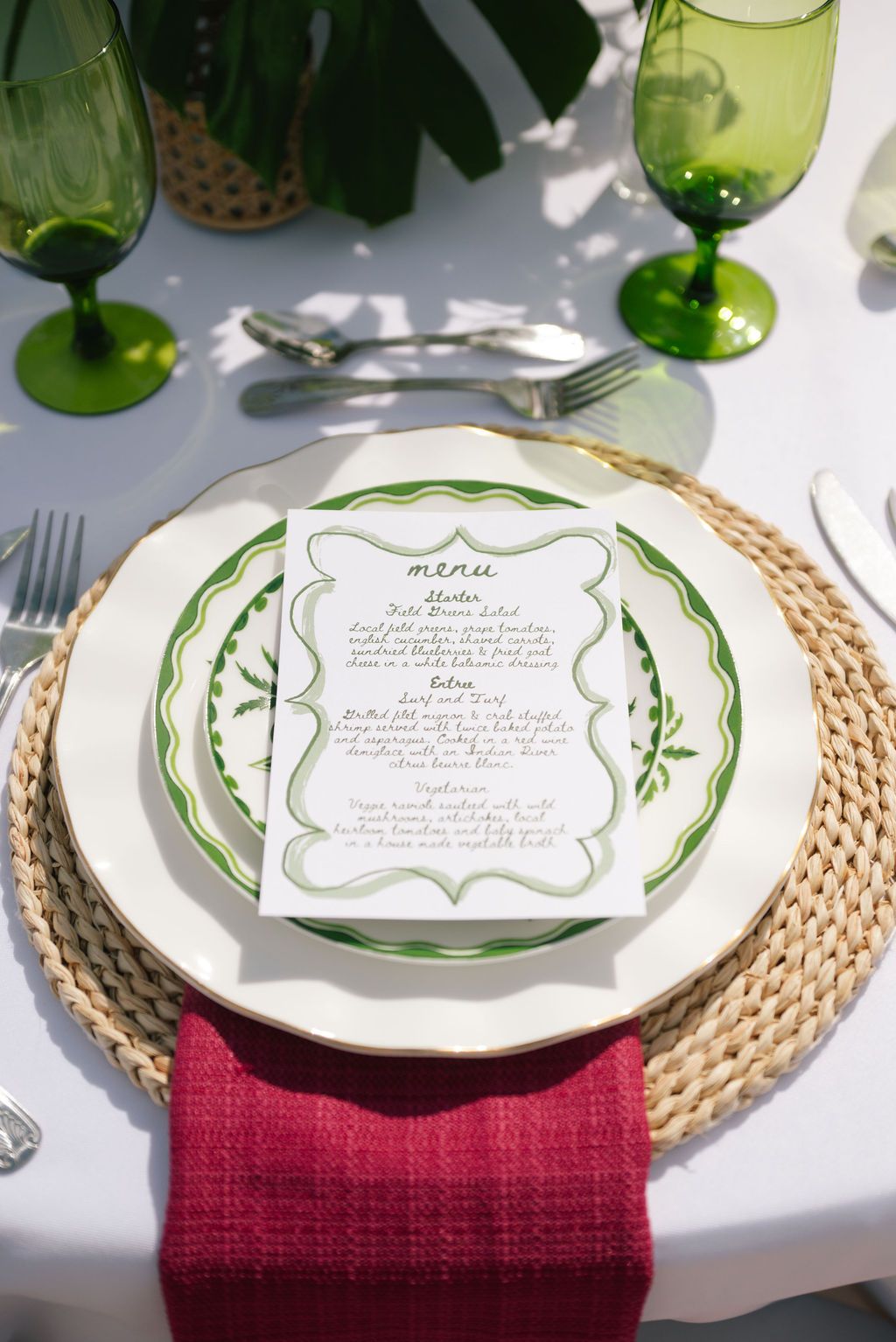 Elegant place settings featuring green-trimmed plates with menu cards on woven chargers.