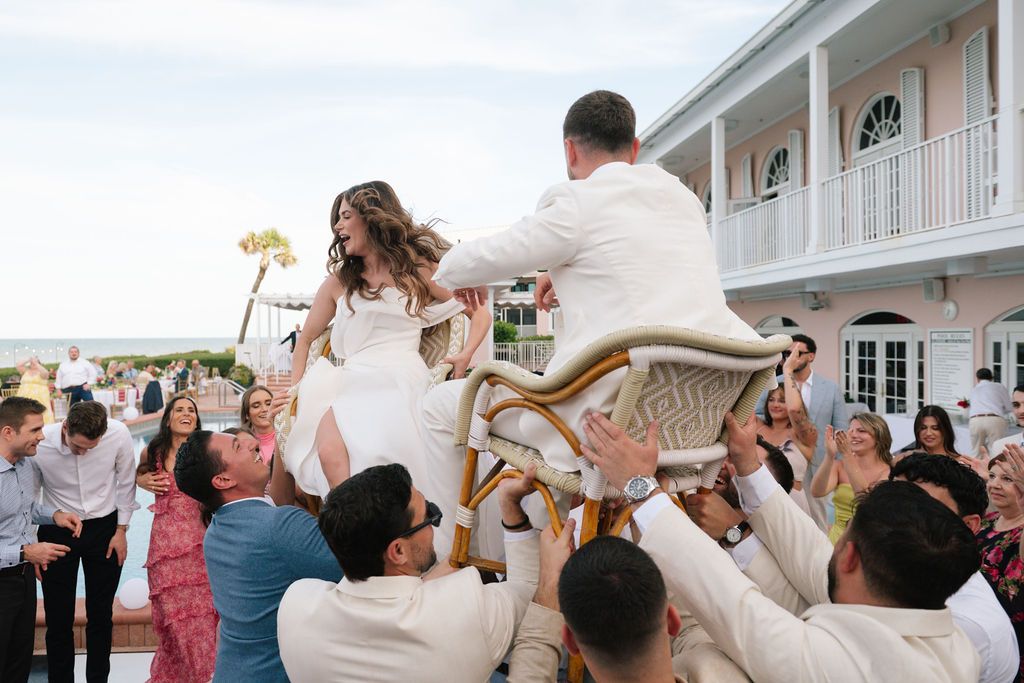 Wedding party dances and celebrates on a black and white checkered dance floor at a coastal venue.