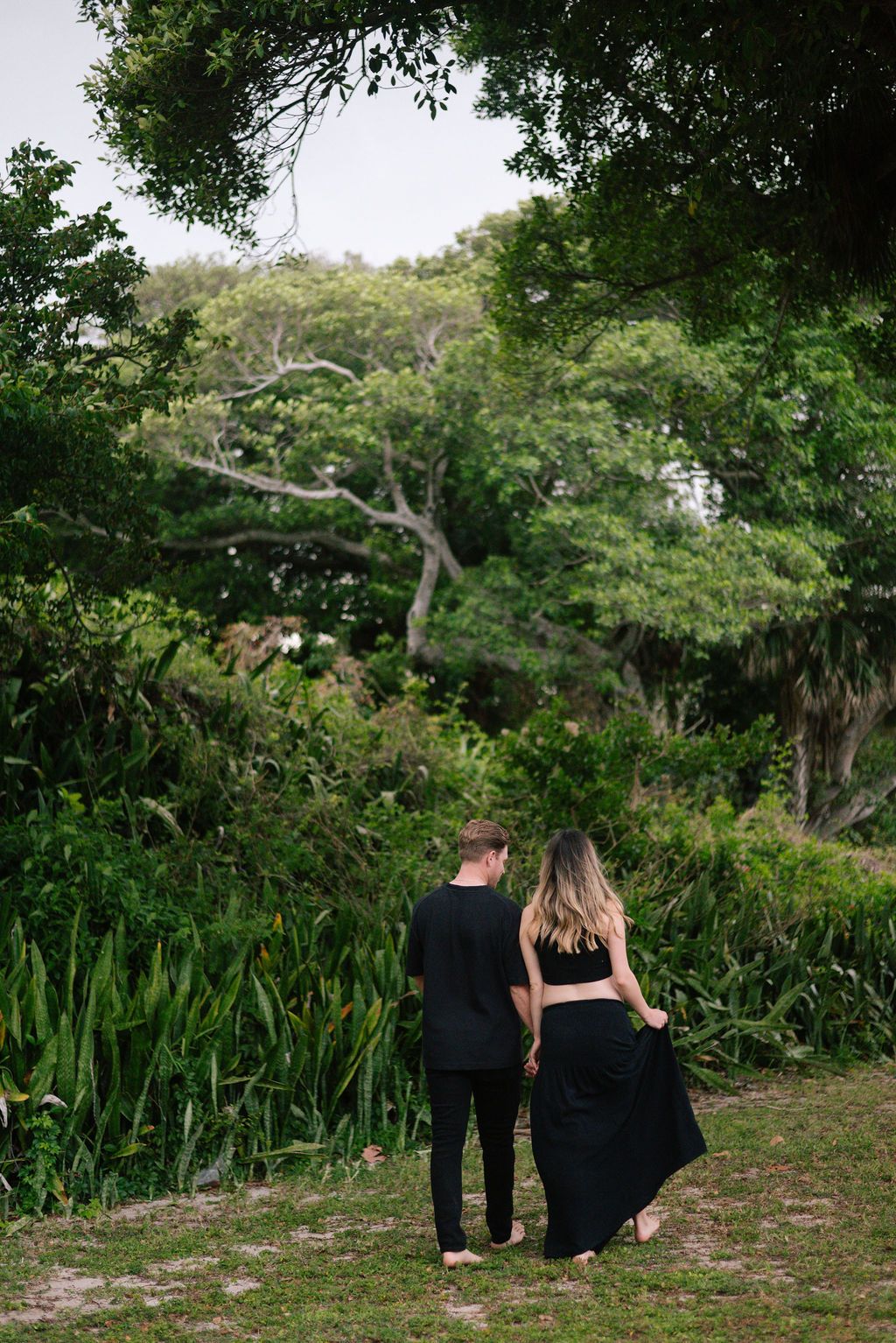 Couple walking together through a scenic garden path surrounded by greenery.