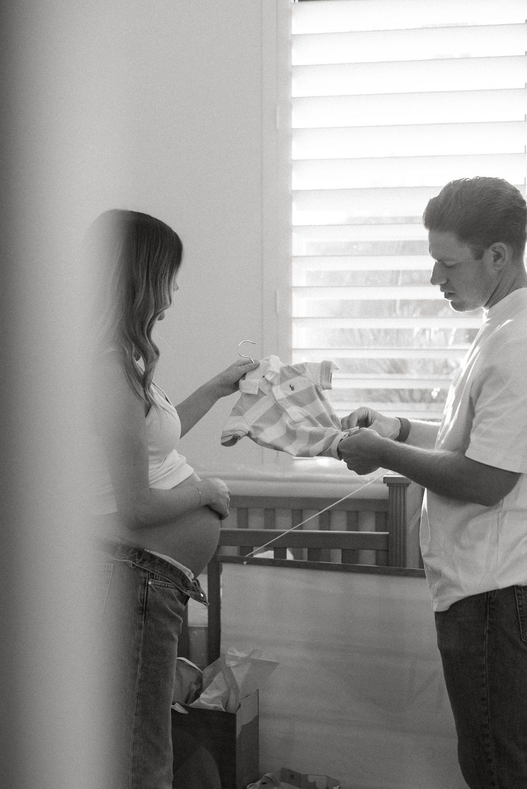 Couple in casual attire sharing an intimate moment by a window.