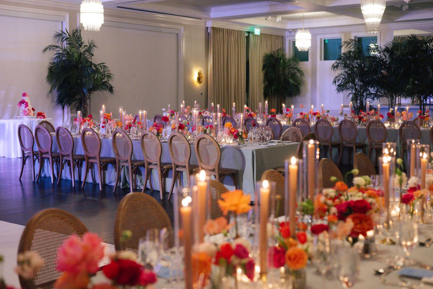 Elegant wedding reception tables set with glowing candles and floral centerpieces in a grand ballroom.