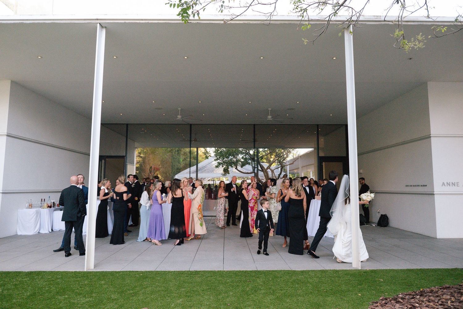 Wedding reception setup in a modern white minimalist space with guests gathering.