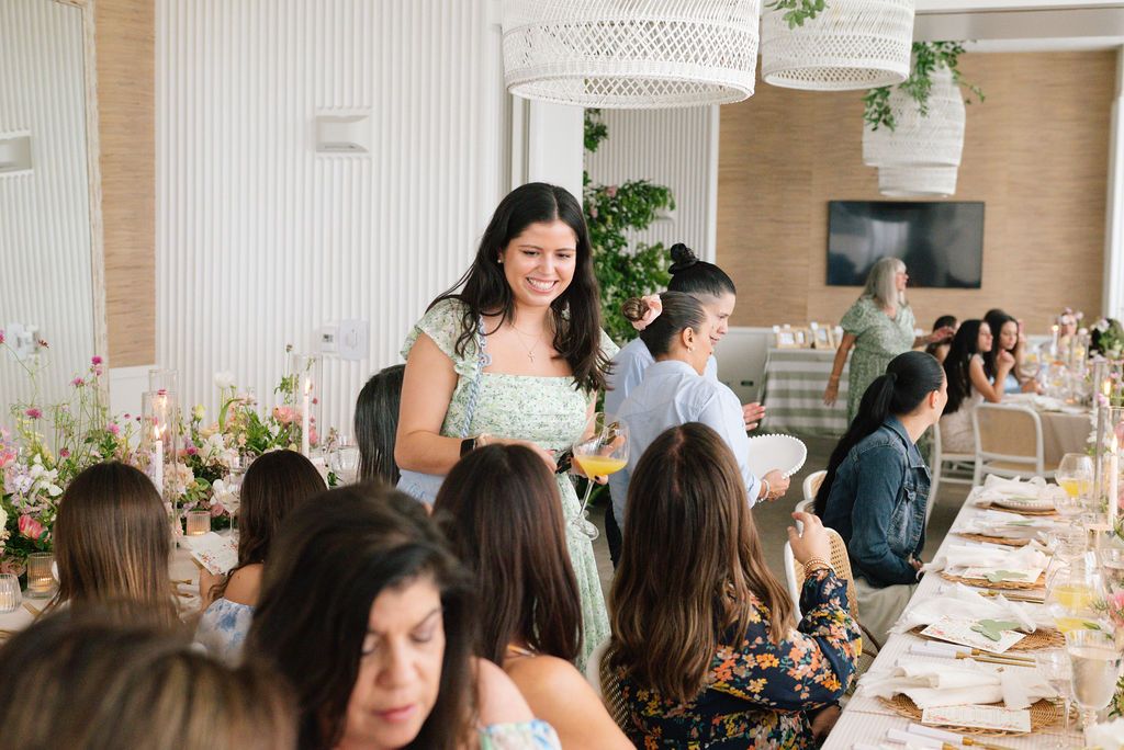 Elegant brunch party with guests seated at a beautifully decorated table with floral centerpieces.