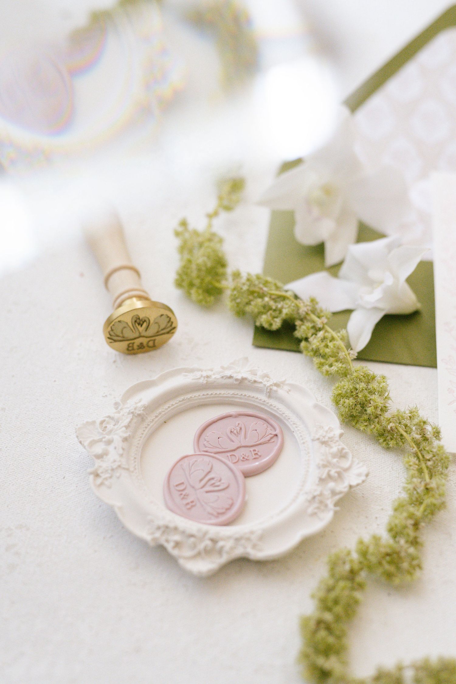 Vintage wax seal stamps on ornate white dish with green floral accents.