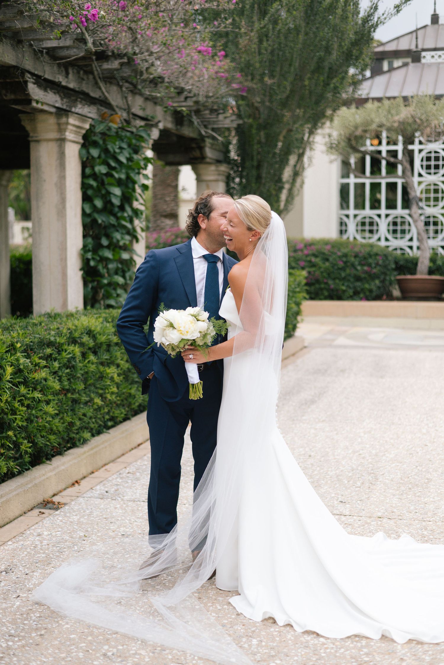 Wedding couple sharing intimate moments on a gravel pathway with classic architectural details.