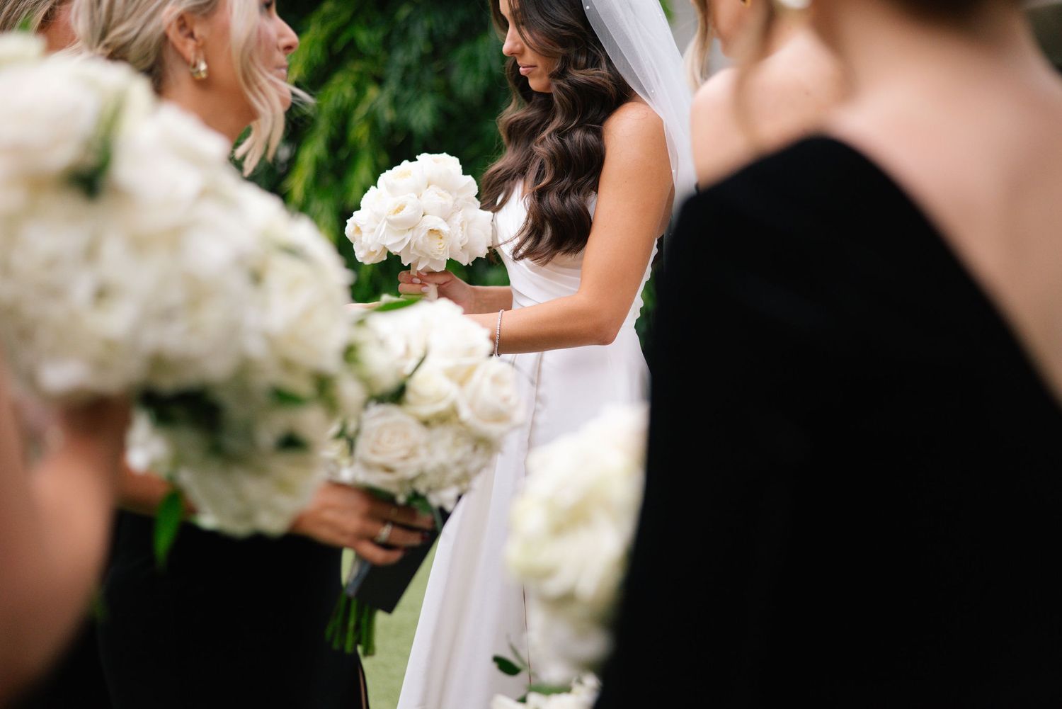 Bridal party in black and white attire posing for formal outdoor wedding photos.