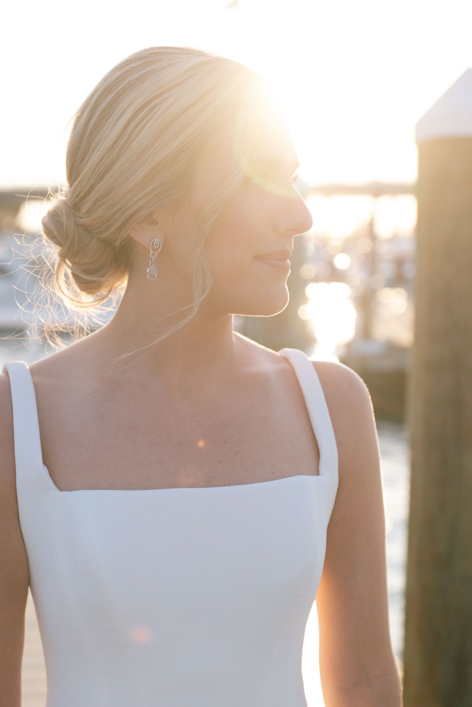 Elegant bride in square neck wedding dress backlit by golden sunset light.