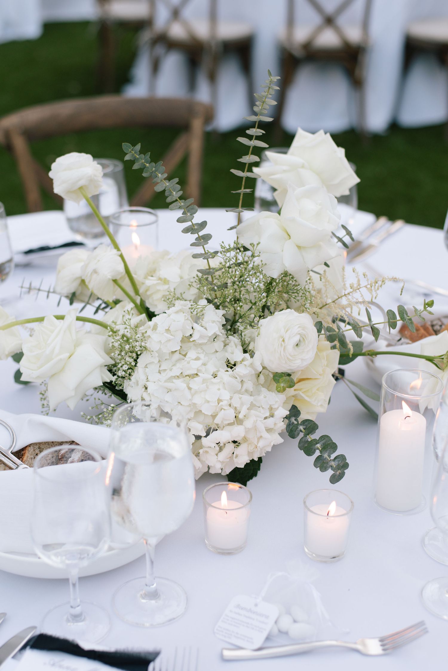 Elegant white floral centerpieces with candles on a formal dining table setting.