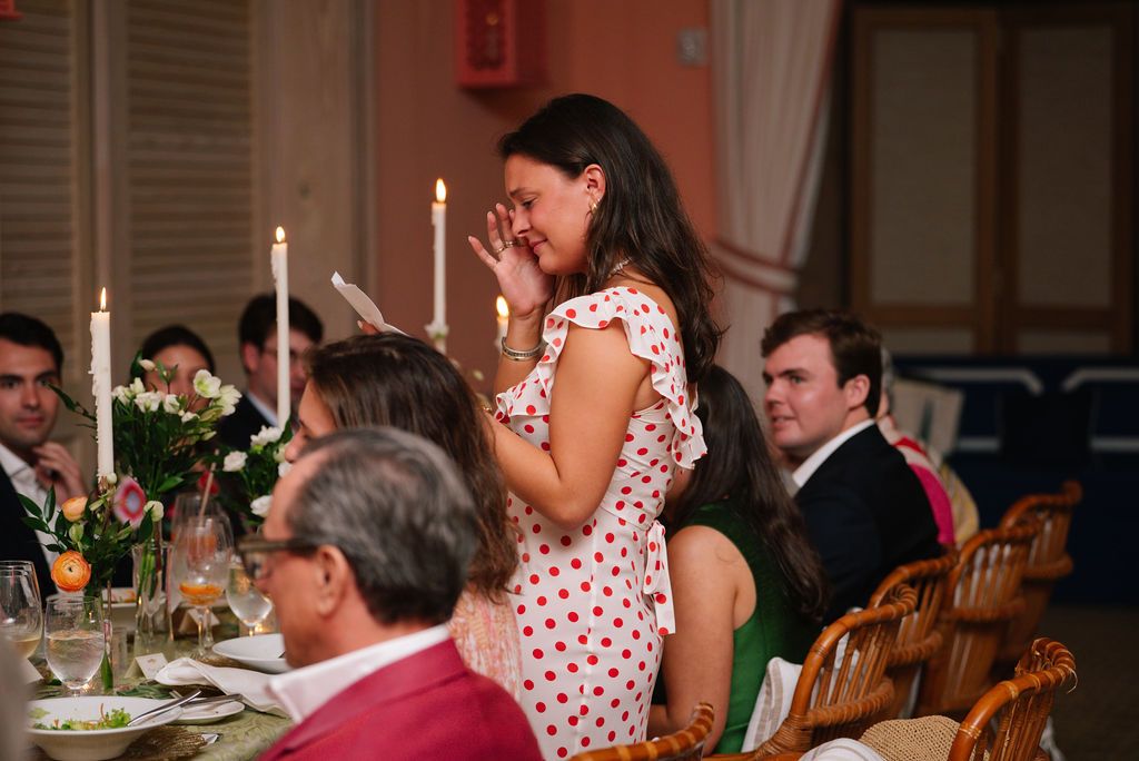 Guests sharing emotional moment during formal dinner party with candlelit table.