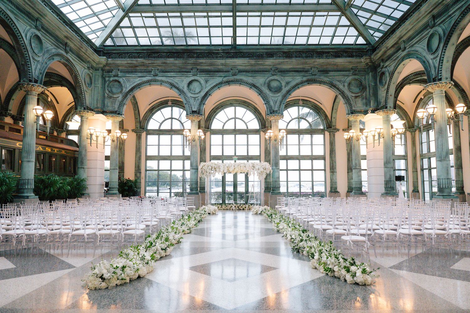 Panoramic view of elegant wedding ceremony space with glass ceiling and classic architecture.