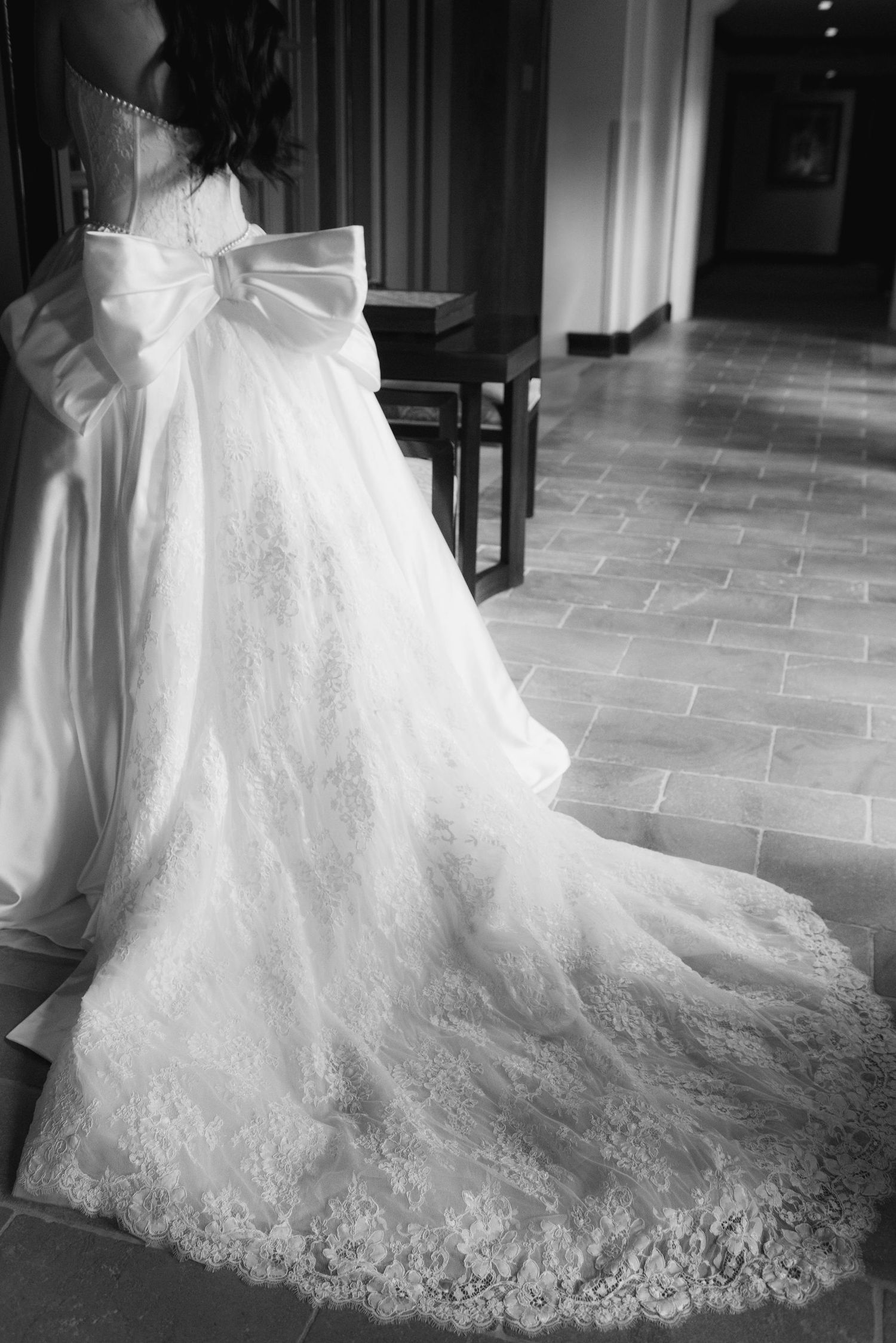 Black and white photos showcasing the intricate lace train of a wedding gown.