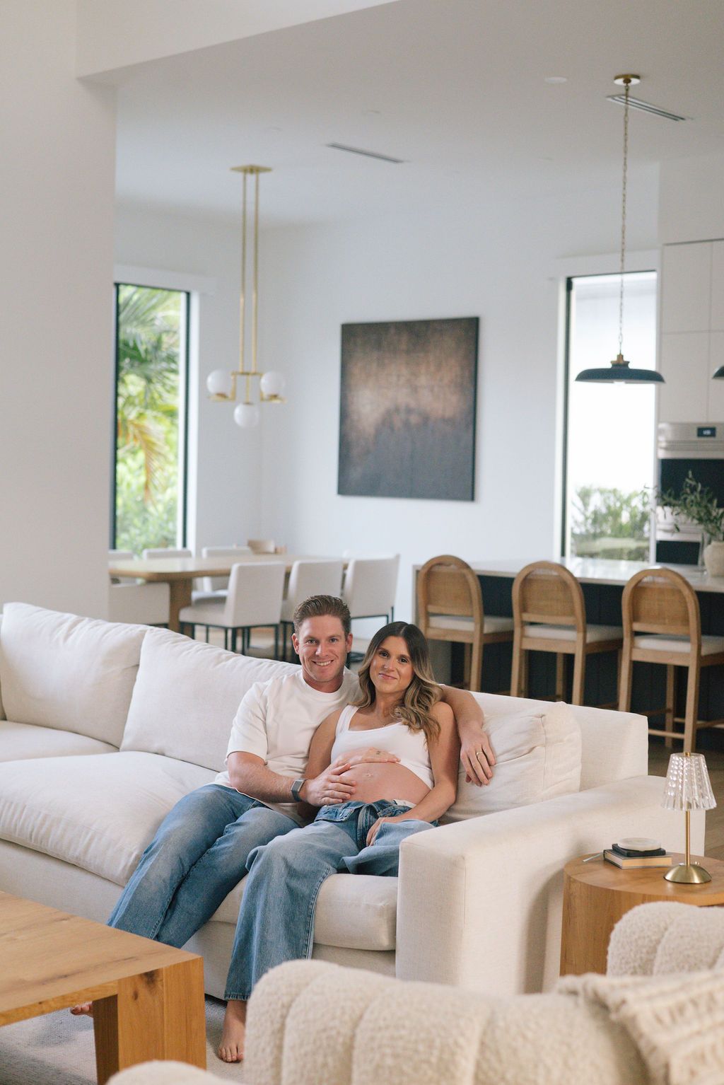 Couple relaxing on white sectional sofa in an open-concept modern living room.