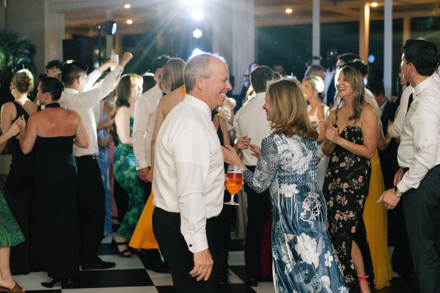 Wedding guests dancing and socializing during an evening reception celebration.