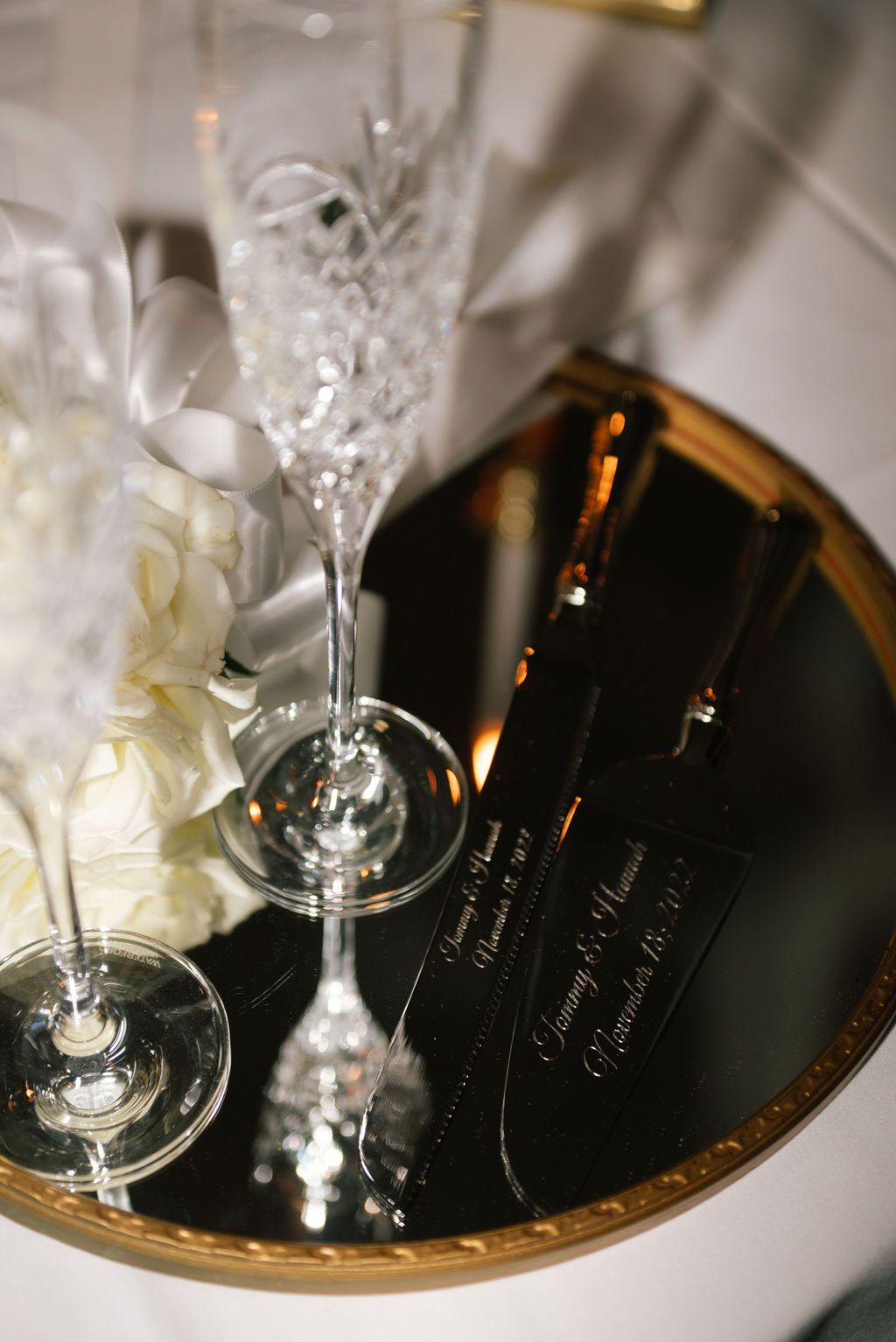 Crystal champagne glasses and floral arrangements on gold mirrored charger plates.