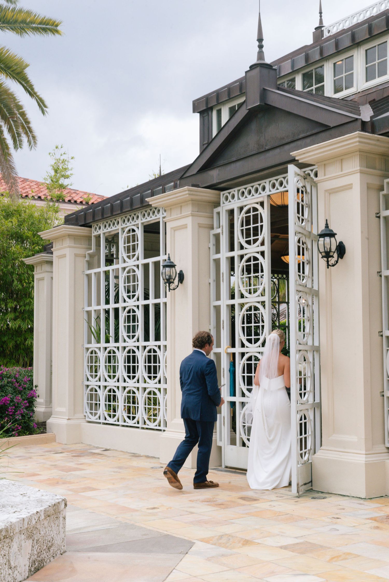 Elegant white building entrance with decorative iron windows and stone walkway.
