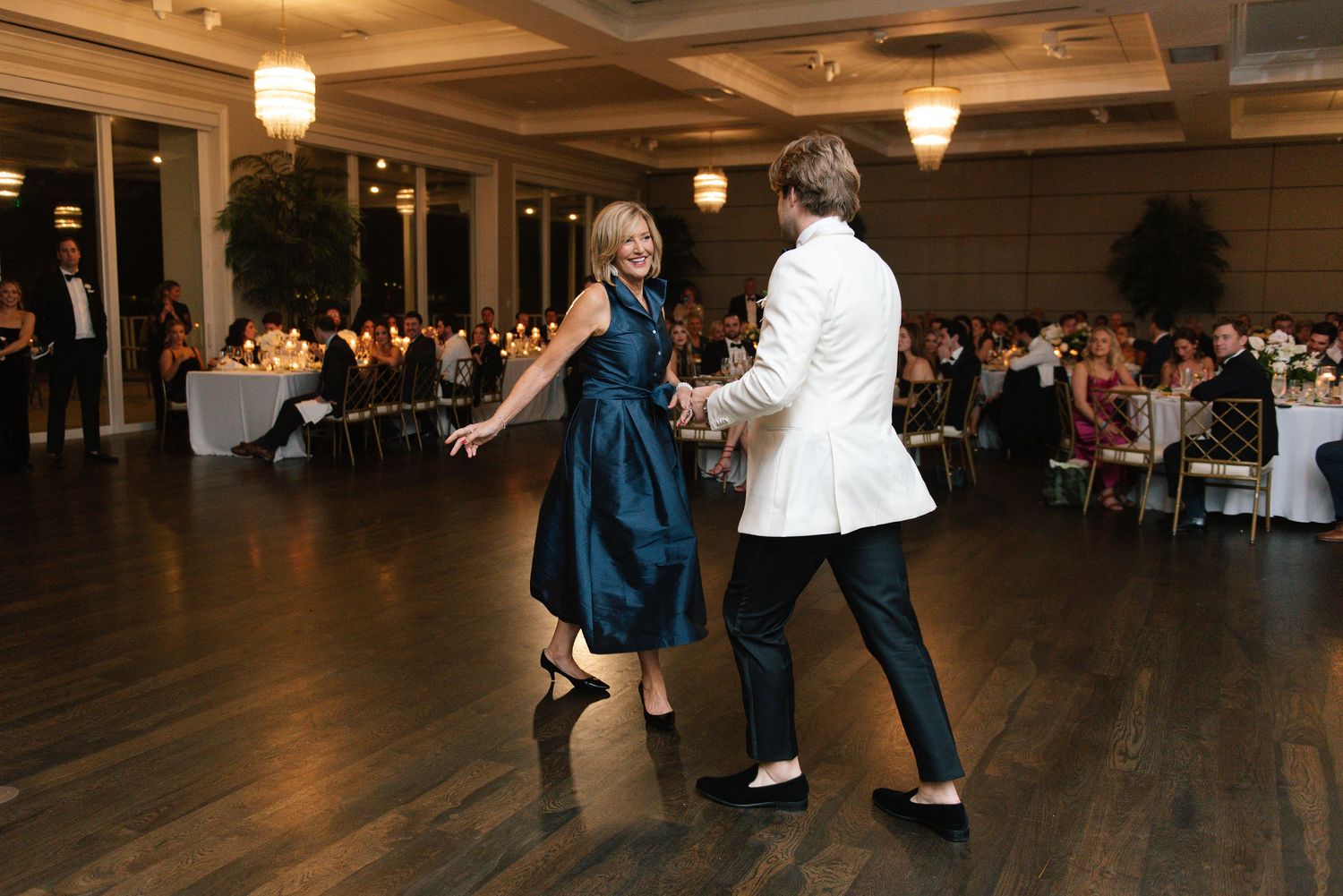 Couple dancing together on a wooden floor at an elegant reception event.