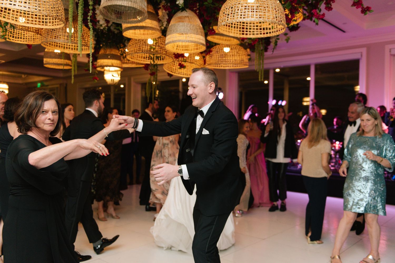 Wedding reception dance floor with hanging wicker lamps and purple lighting.