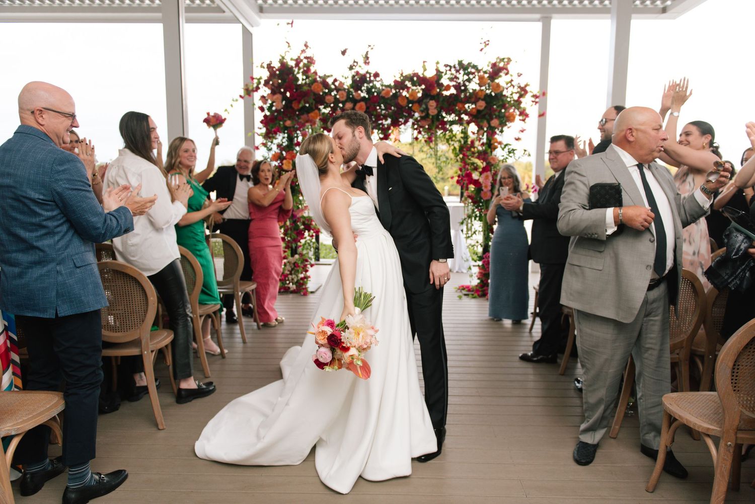 Wedding reception guests seated at tables celebrate during an indoor event with bright decor.