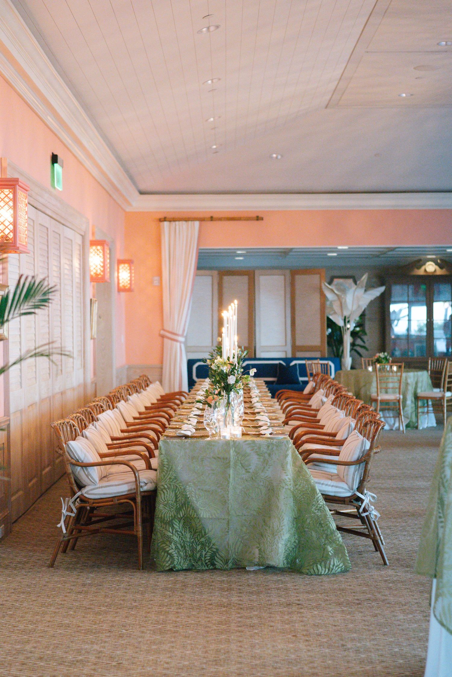 Elegant banquet hall with long tables set with green linens and white chairs.