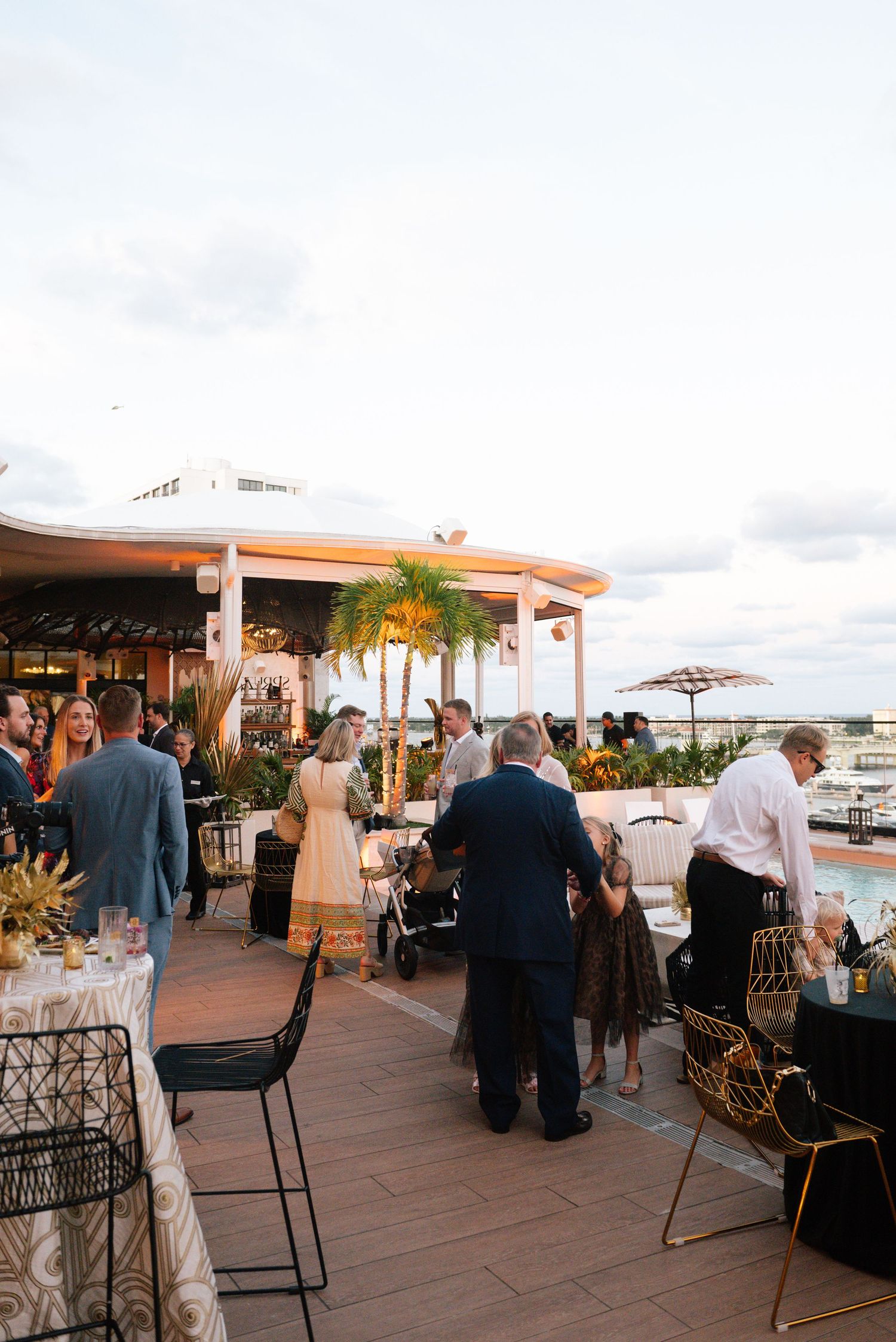 Outdoor reception venue with guests mingling on a terrace during sunset.