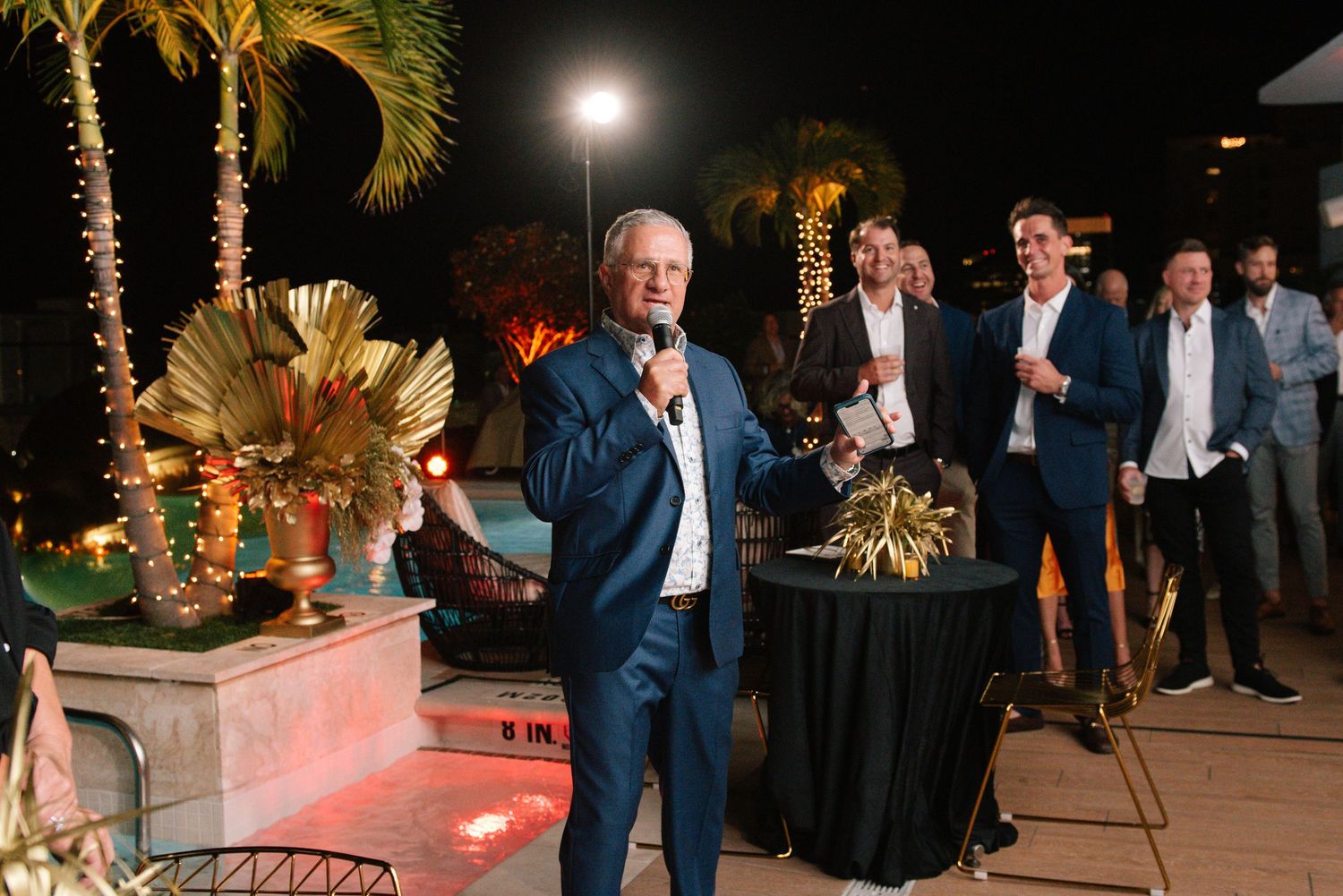Evening outdoor event space with palm trees and ambient lighting.