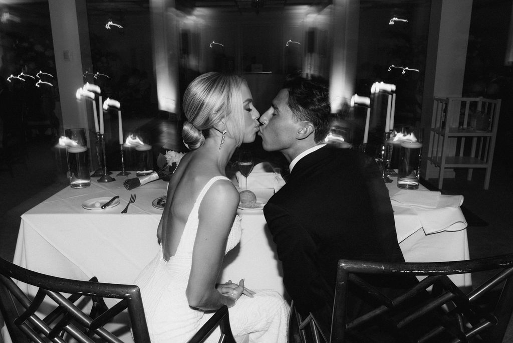 A romantic black and white photo of a couple sharing an intimate moment at their wedding reception.