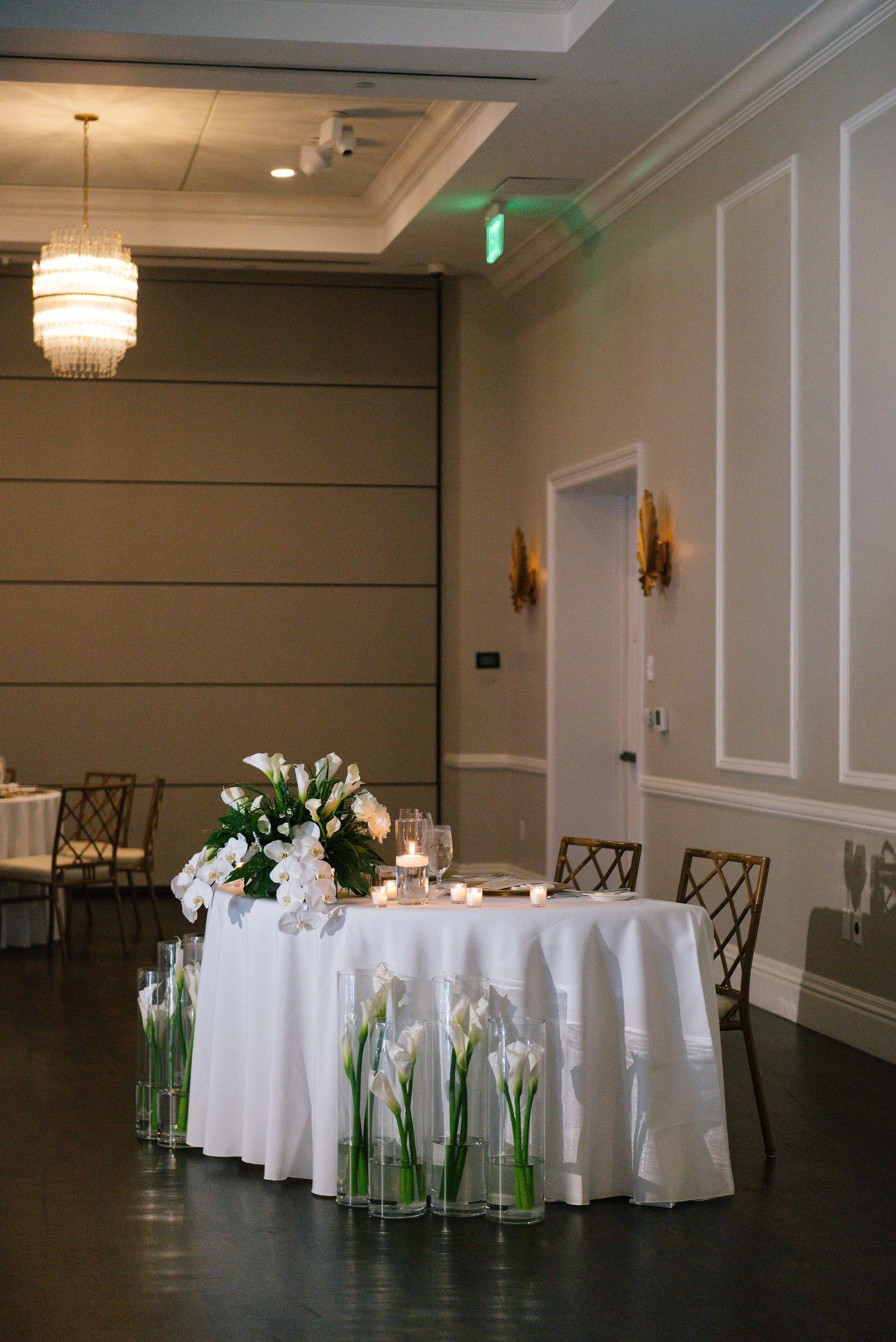 Wedding reception ballroom with round tables dressed in white linens and floral centerpieces.