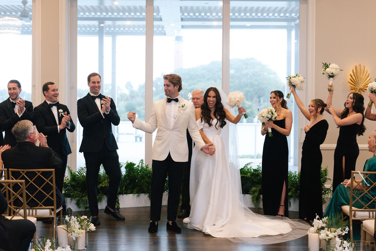 Wedding party dancing and celebrating during a joyful reception in an elegant indoor venue.