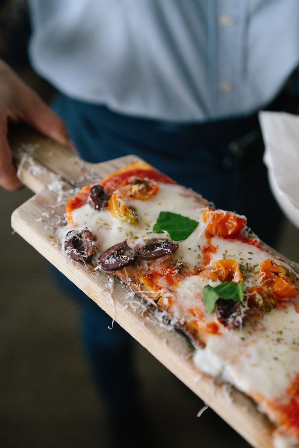 Flatbread pizza with roasted tomatoes and herbs served on white marble board.