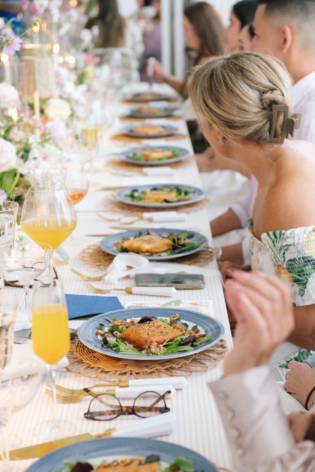 Close-up of brunch table settings with plated meals and orange juice in elegant glassware.