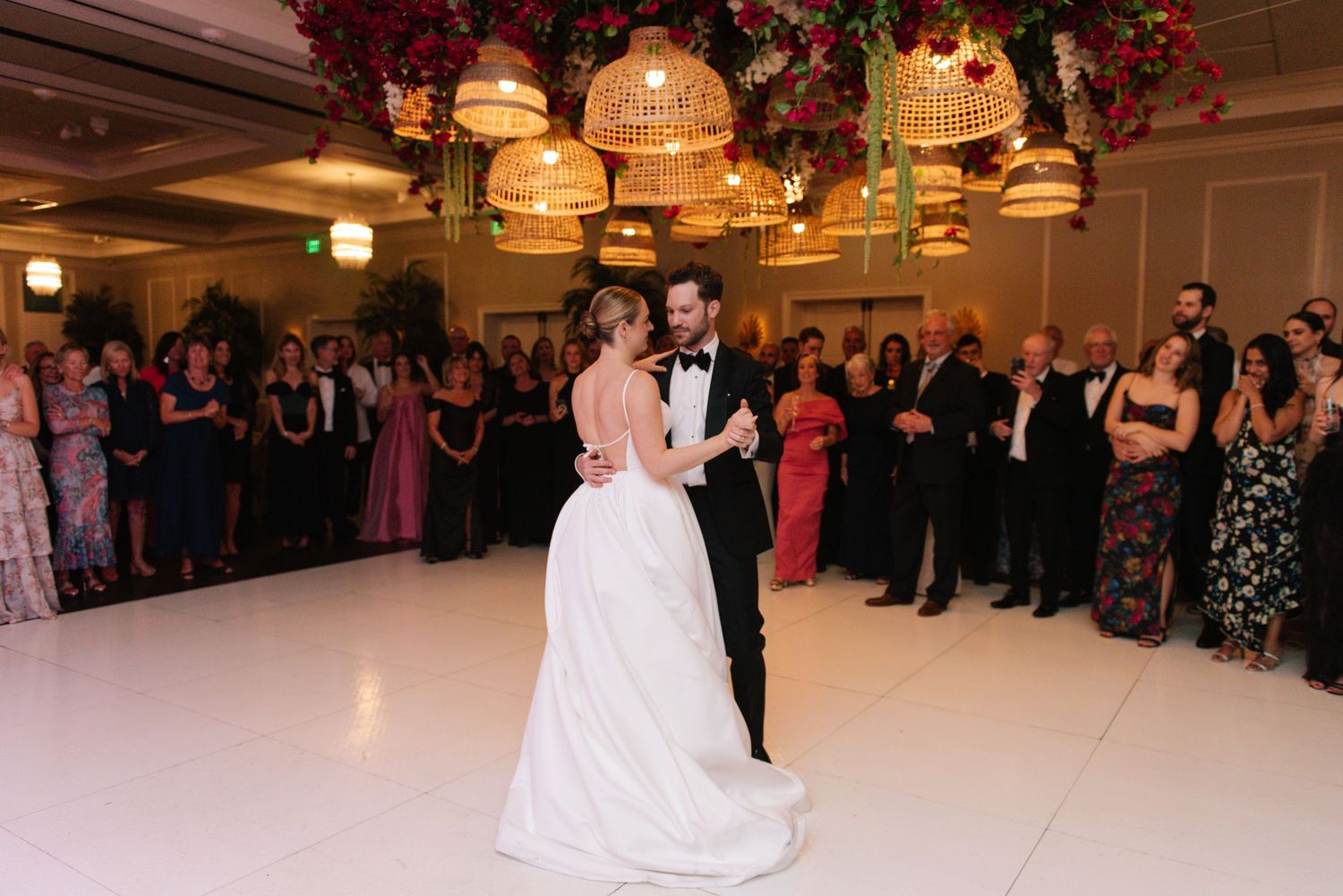 Newlyweds sharing their first dance surrounded by guests at an elegant reception.