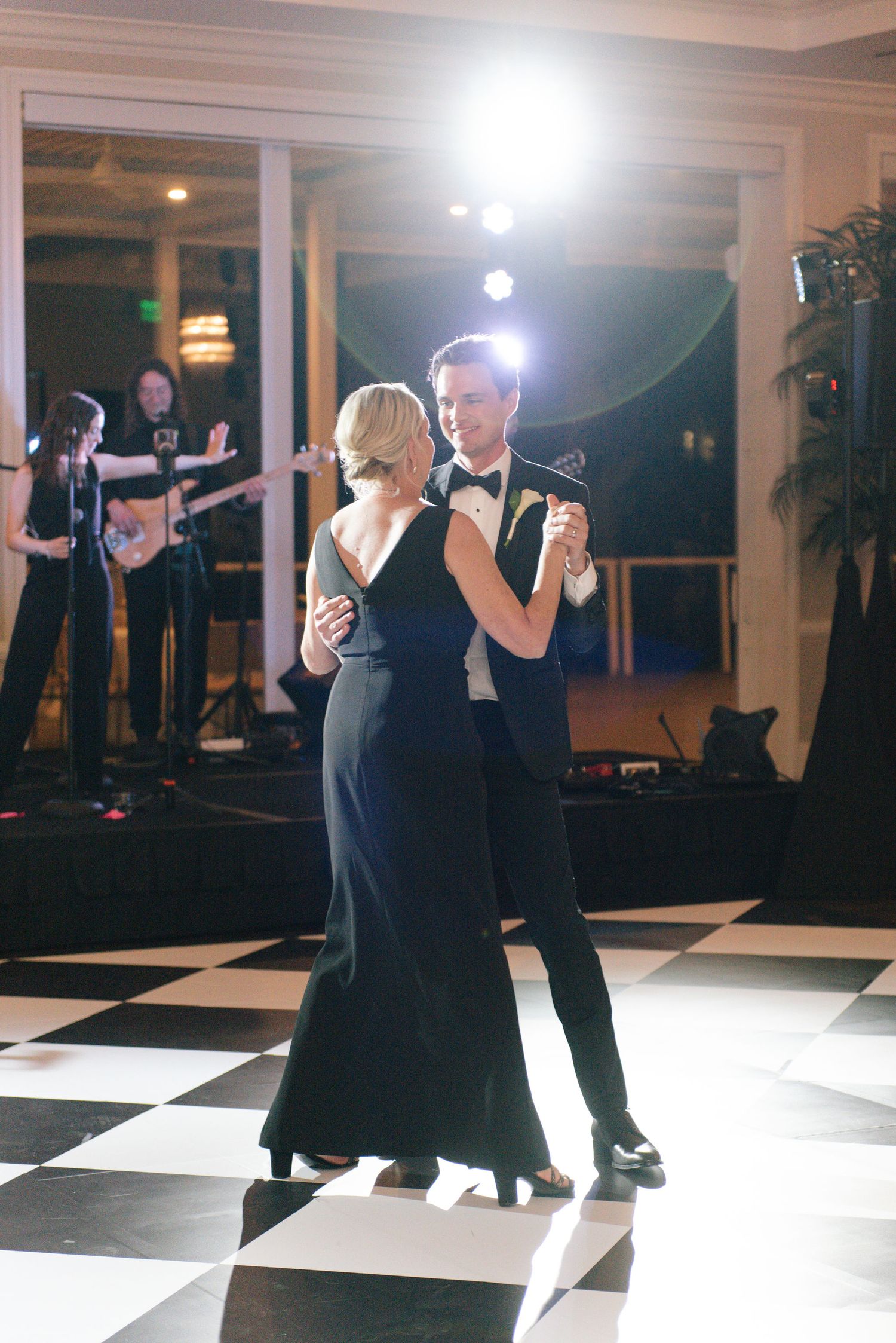 Couples dancing on a black and white checkered floor at an elegant wedding reception.