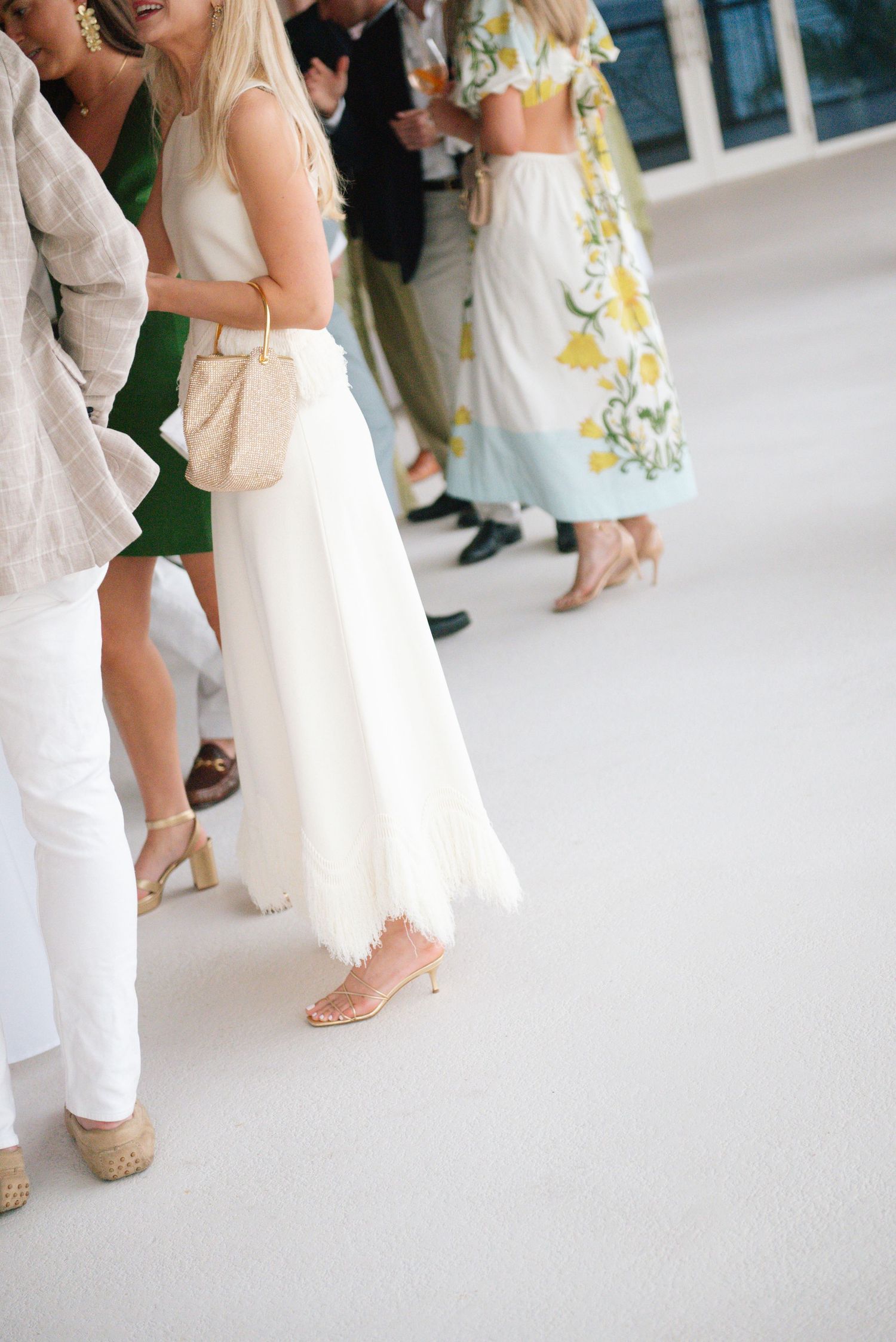 Wedding guests in white and cream colored attire mingle during an elegant reception celebration.
