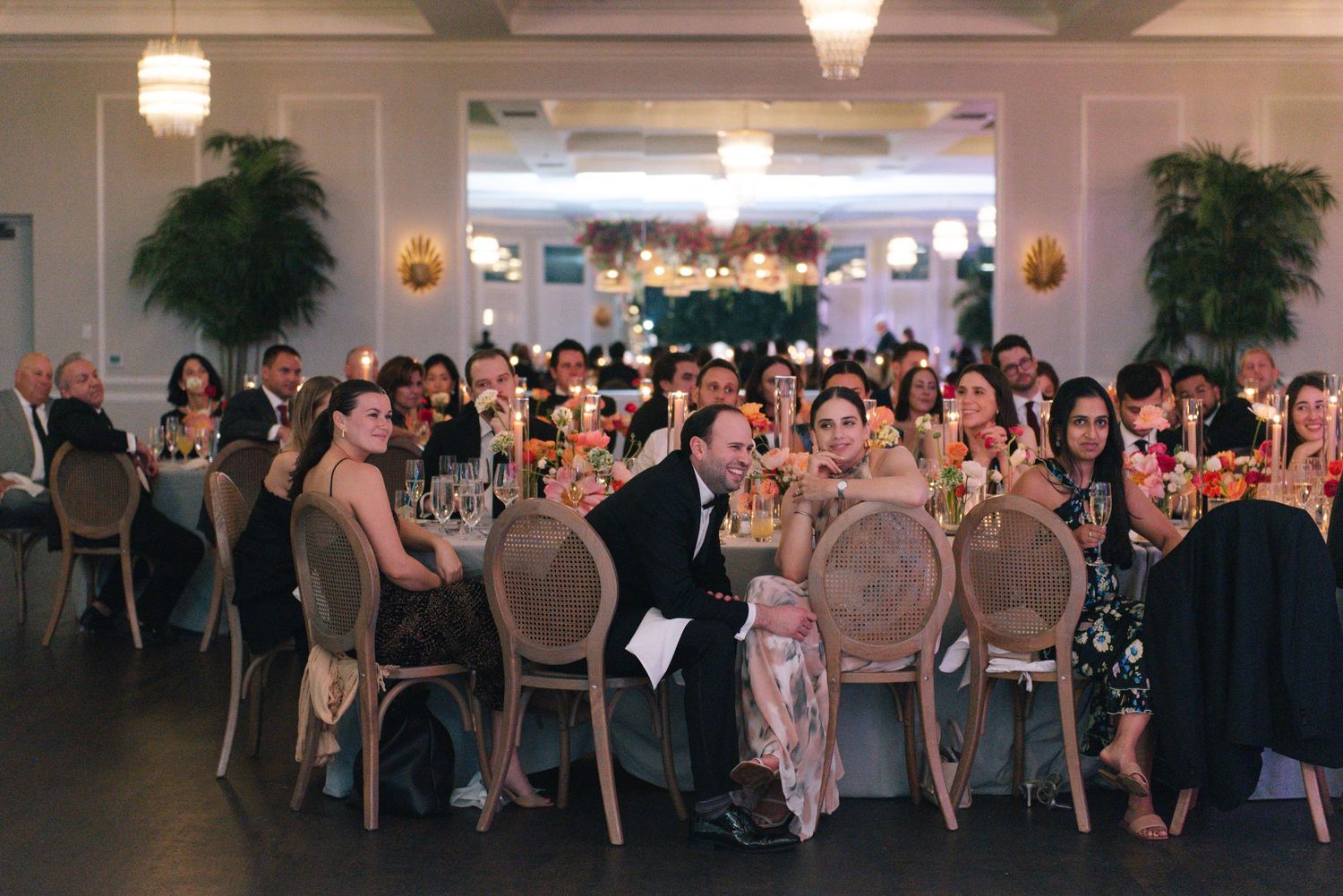 Wedding reception ballroom with elegant table settings and chandeliers.