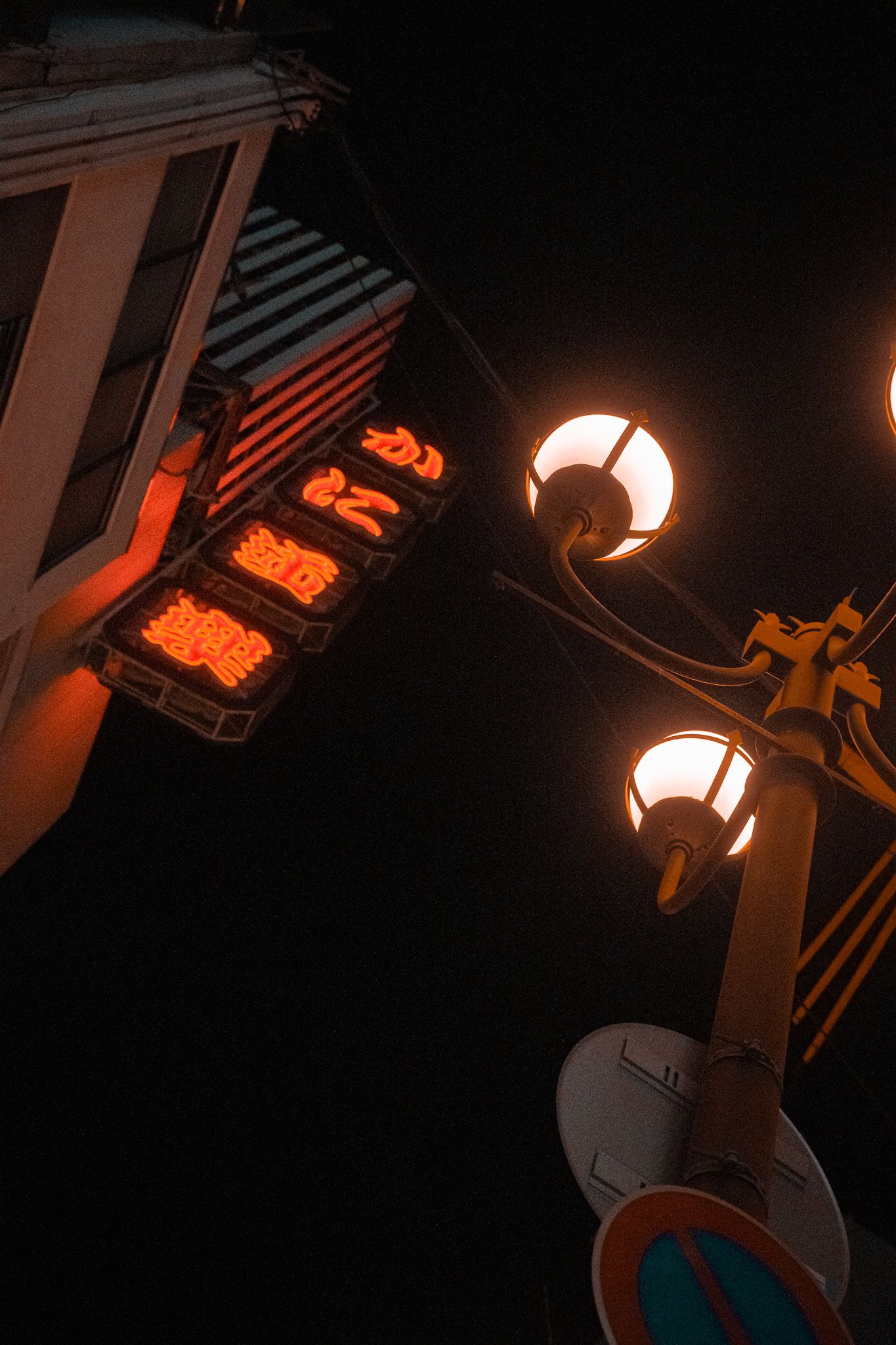 Orange lantern glowing against dark architectural details in low light conditions.